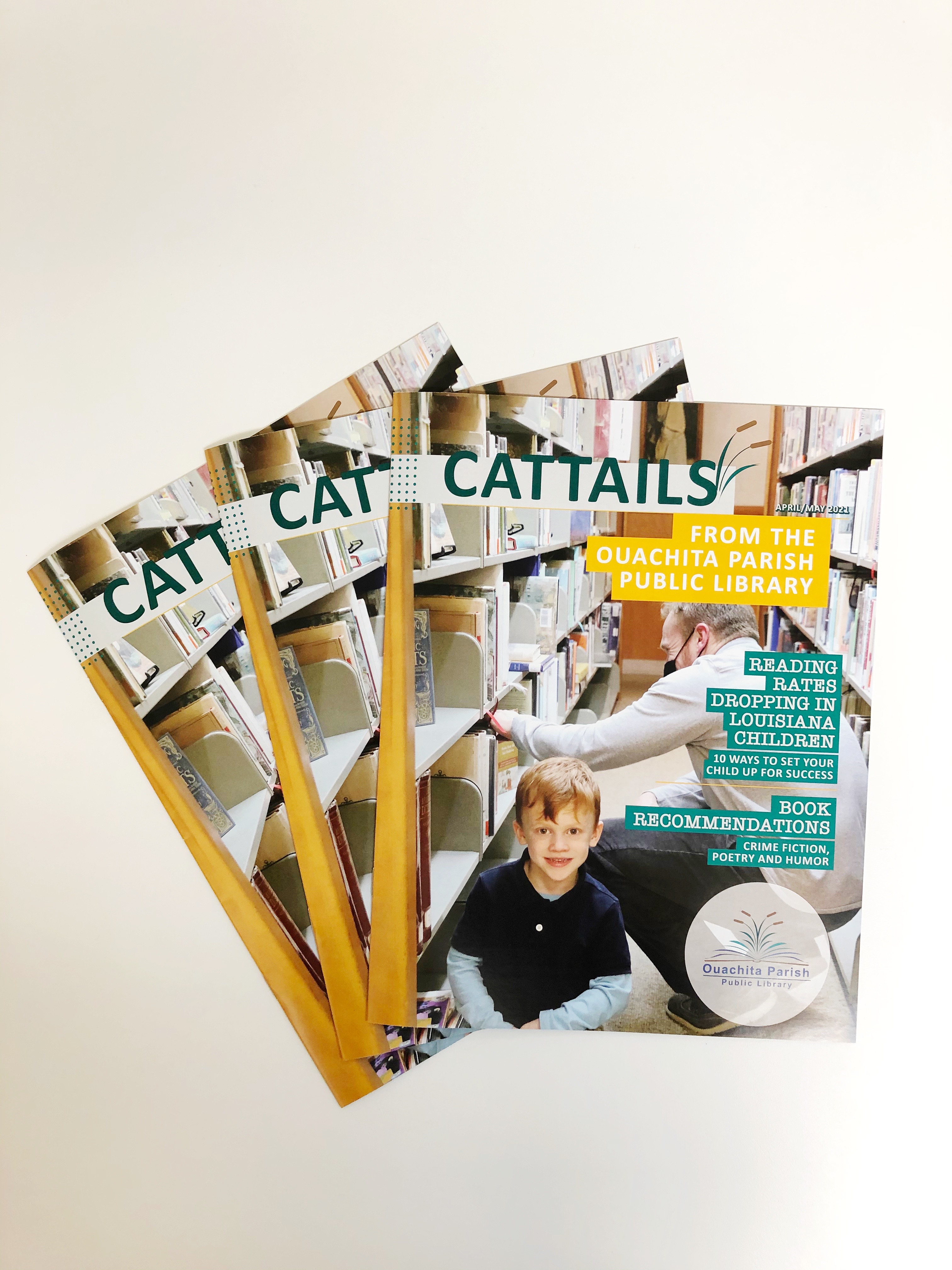 Three issues of the April/May Cattails lay on a white table.