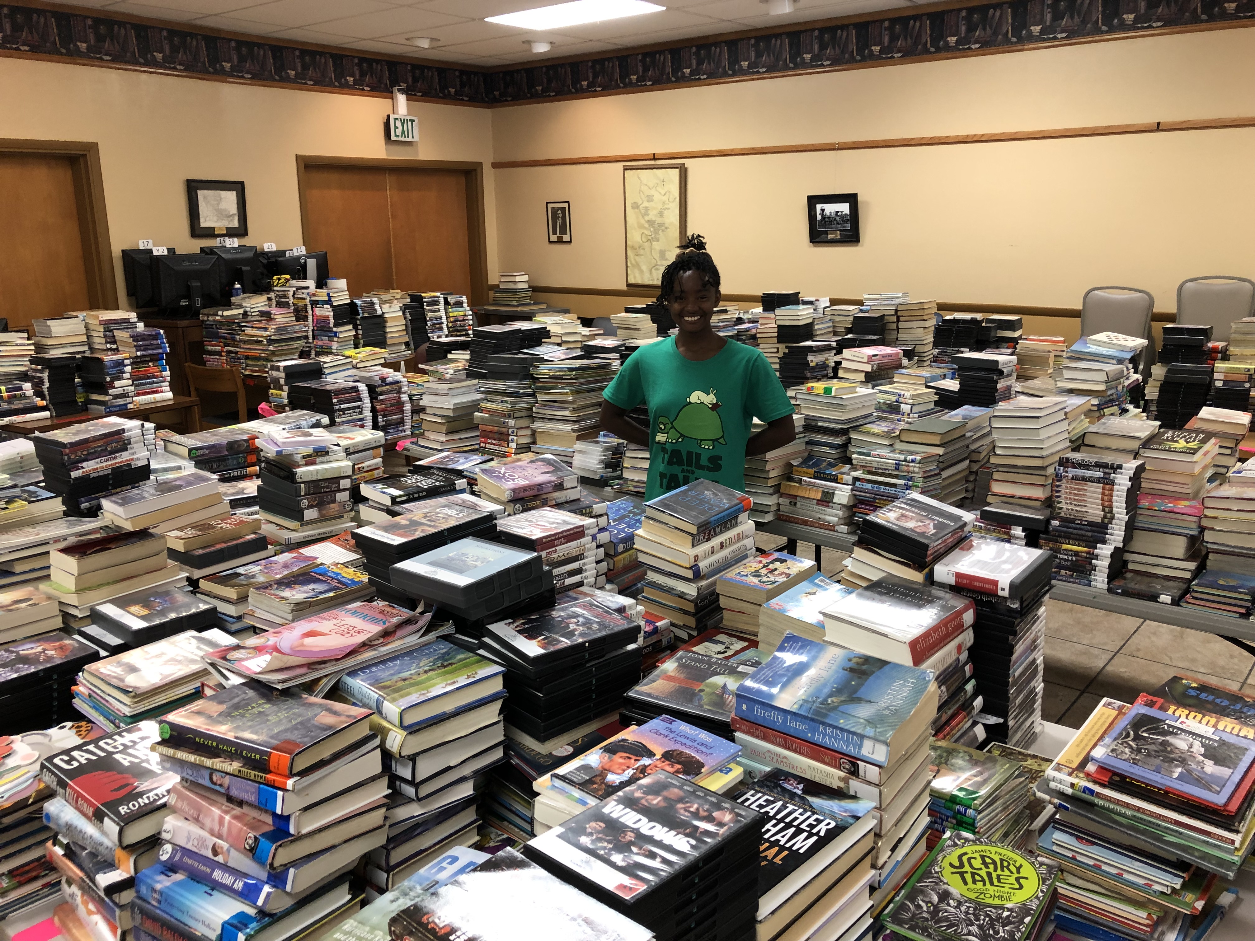 A woman stands in a room surrounded by books.