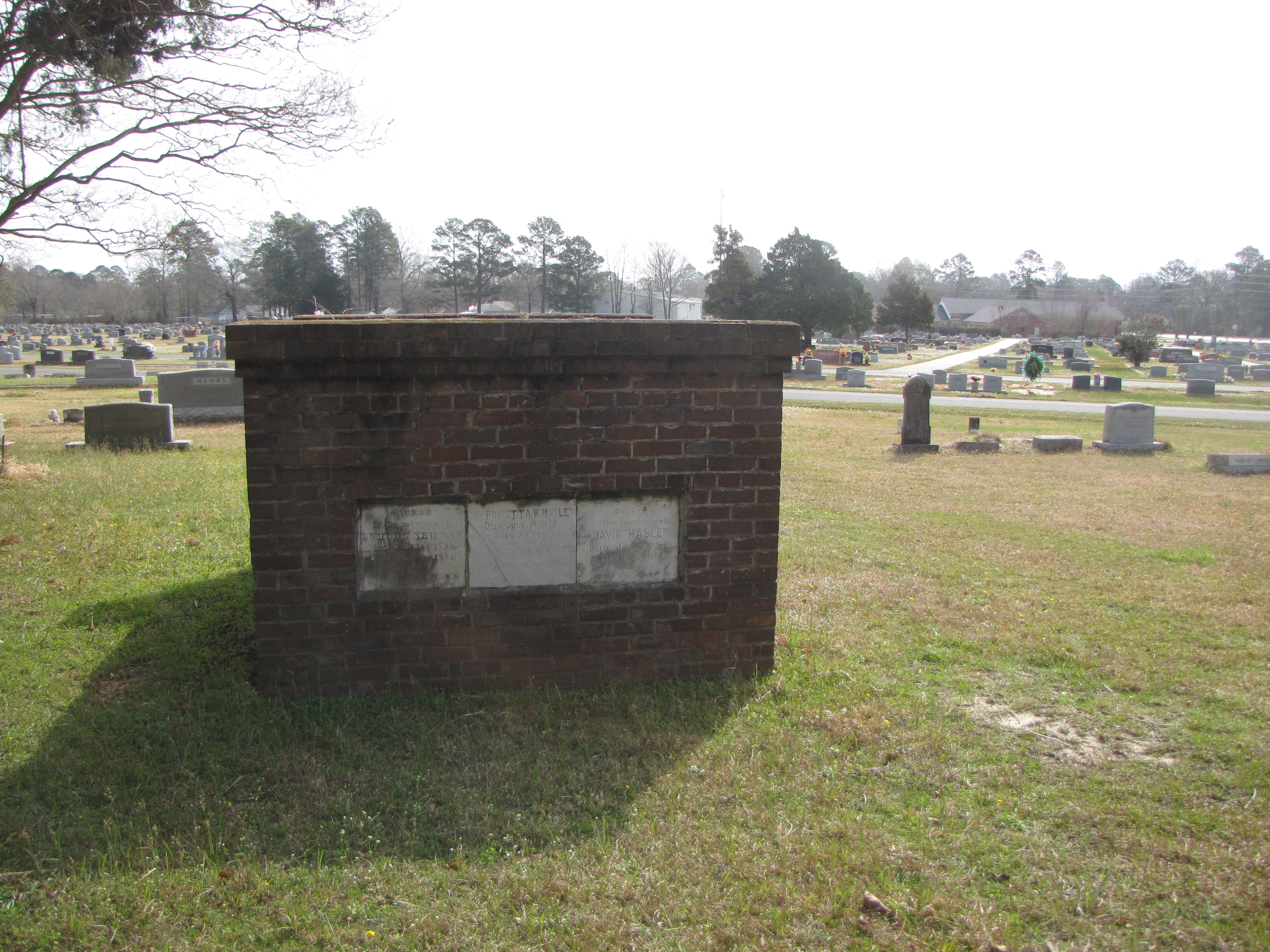 This is an image of a brick mausoleum on a green lawn. 